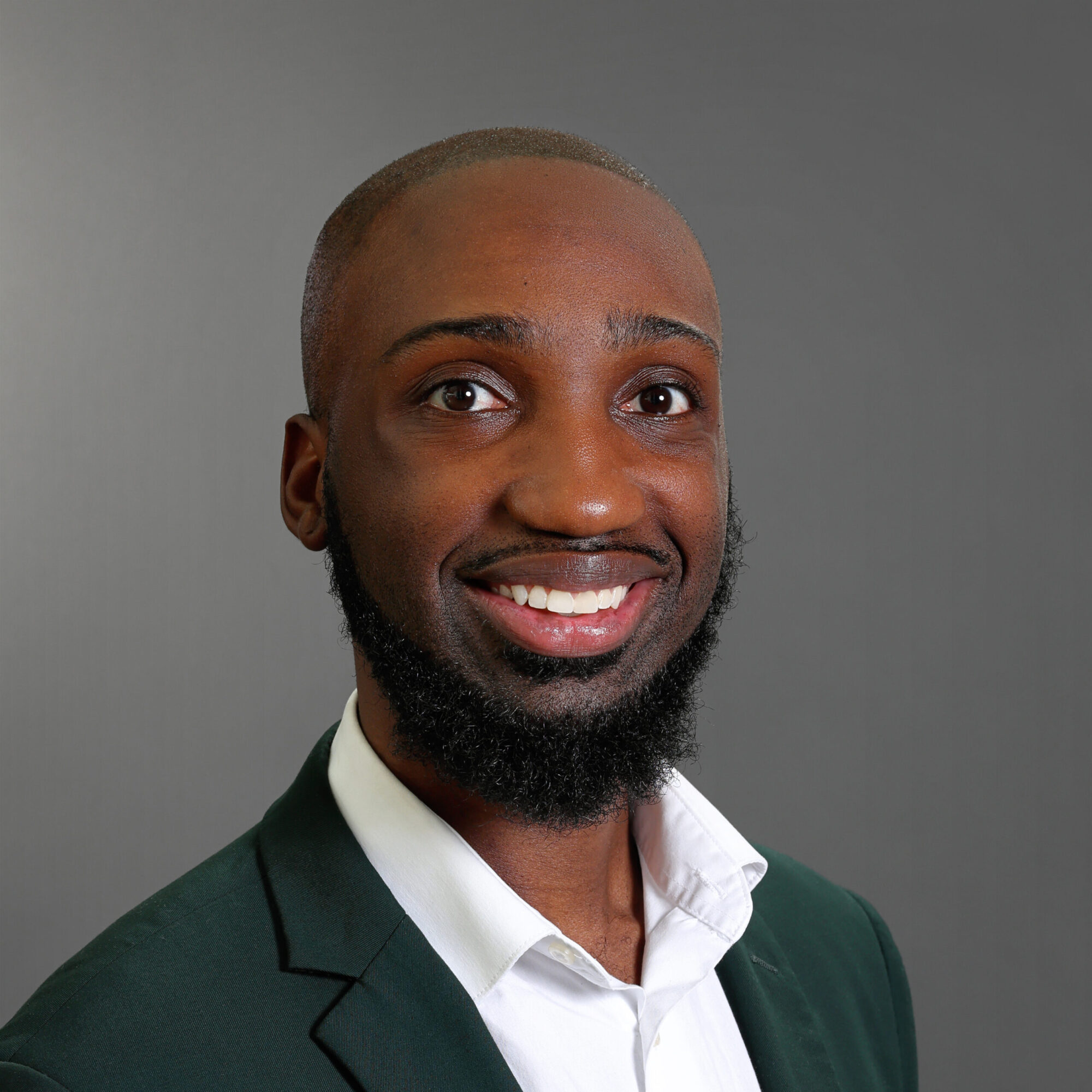 Professional headshot of Harry Dent smiling, wearing a dark green blazer and white dress shirt against a gray background.