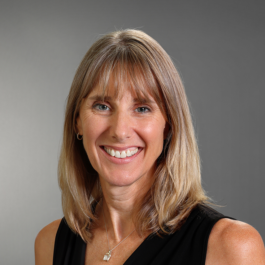 Professional headshot of Michelle McCallum smiling, wearing a black sleeveless top and a delicate necklace against a gray background.
